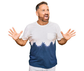 Sticker - Handsome middle age man wearing casual tie dye tshirt crazy and mad shouting and yelling with aggressive expression and arms raised. frustration concept.