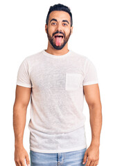 Poster - Young hispanic man wearing casual clothes sticking tongue out happy with funny expression. emotion concept.