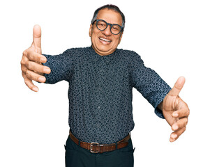 Sticker - Middle age indian man wearing casual clothes and glasses looking at the camera smiling with open arms for hug. cheerful expression embracing happiness.