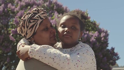 chest up slowmo portrait of african american mother and little daughter smiling at camera and embrac