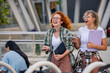 © lordn - A couple of cheerful female university students in front off the university building holding books, smiling
