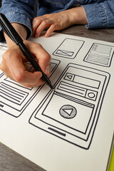 UI designer sketches the user interface of a web application for a mobile phone. A developer creates a prototype for a smartphone.
