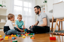 Father Talking To Sons On Floor With Module Blocks