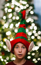 Preteen Boy In Christmas Elf Hat With Christmas Tree Light Bokeh