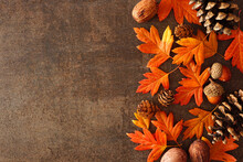 Colorful Autumn Leaves, Nuts And Pine Cones. Side Border Over A Rustic Dark Background. Above View With Copy Space.
