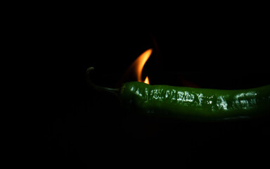 flaming green chili pepper close up on dark background