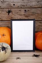 Composition Of Halloween Decoration With Pumpkins And Frame With Copy Space On Wooden Background