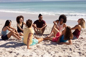 Wall Mural - Multi-ethnic group of male and female sitting on the beach