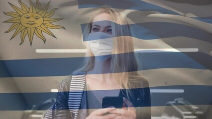 Sticker - Animation of flag of uruguay waving over caucasian woman wearing face mask in city street