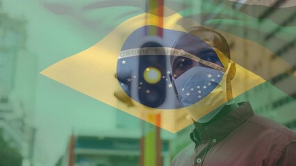 Wall Mural - Animation of flag of brazil waving over african american man wearing face mask in city street