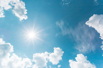 Wall Mural - Sunny background, blue sky with white clouds and sun. The natural blue background has a breeze on a bright day in the summer.The sky and clouds are not the same shape as the weather.