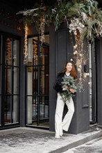 Portrait Of Young Woman Posing Near Mistletoe Decorated Door