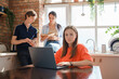 © Fxquadro - Portrait of woman using laptop at table and her two friends reading book at her back.