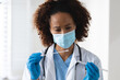 © Wavebreak Media - Mixed race female doctor wearing mask inspecting patient swab test