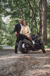 © perfectlab - Young beautiful couple hugging, sitting on a motorcycle, travel together on a forest road