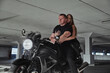 © perfectlab - Young couple hugging sitting on a motorcycle in underground parking garage
