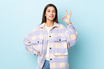 Wall Mural - Young caucasian woman isolated on blue background showing ok sign with fingers