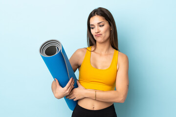 Sticker - Young sport woman with mat isolated on blue background with sad expression