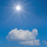 Fototapeta Las - sparkle sun above dense cumulus clouds on blue sky background