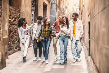 Happy multiracial group of friends walking on city street - Cheerful young people hanging outside together - Friendship concept with guys and girls having fun outdoors