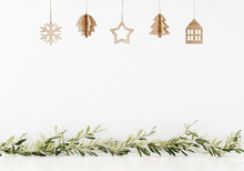 Simple Minimal Christmas Wall Mockup With Wooden Hanging Decoration And Green Garland Of Branches On Empty White Background. 3d Illustration, 3d Rendering