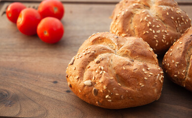 Delicious buns with sesame and cherry tomatoes on a cutting board.