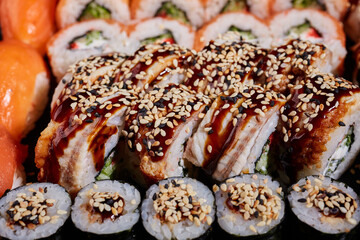 Sticker - Close up of sushi rolls drizzled with sauce and sprinkled with sesame seeds.