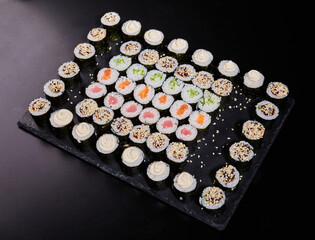 Wall Mural - Different types of maki rolls on a plate on a stone background.