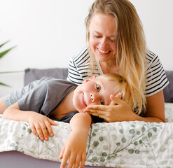 Wall Mural - lovely emotional scene with happy mother and son in bedroom