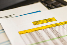 Close Up Shot Of A Print Outs Of Excel Table Of A Bank Loan Amortization Table, Personal Balance Sheet And Laptop. Banking