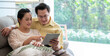 An elderly Asian couple discussing health insurance plans, retirement savings and online shopping via tablets at home.