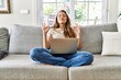 © Krakenimages.com - Beautiful young brunette woman sitting on the sofa using computer laptop at home relax and smiling with eyes closed doing meditation gesture with fingers. yoga concept.