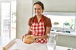 © Krakenimages.com - Young beautiful hispanic woman smiling confident holding bread at the kitchen