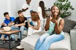 © Krakenimages.com - Group of young friends smiling happy sitting on the sofa. Woman using smartphone at home.