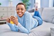 © Krakenimages.com - African american woman drinking coffee lying on sofa at home