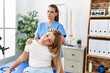 © Krakenimages.com - Woman and girl physiotherapist and patient having rehab session stretching neck at physiotherapy clinic