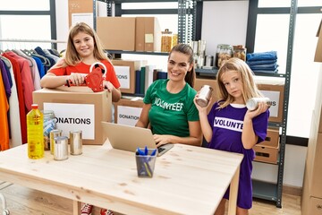 Canvas Print - Mother and daughters wearing volunteer uniform working at charity center