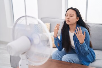 Sticker - Young chinese woman using ventilator sitting on sofa at home