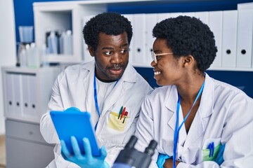 Canvas Print - African american man and woman scientists using touchpad working at laboratory