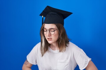 Poster - Blonde caucasian woman wearing graduation cap with hand on stomach because indigestion, painful illness feeling unwell. ache concept.