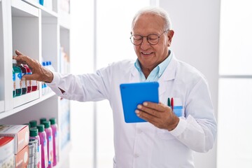 Poster - Senior grey-haired man pharmacist using touchpad at pharmacy