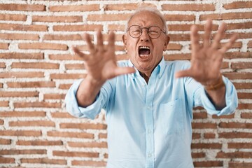 Canvas Print - Senior man with grey hair standing over bricks wall doing stop gesture with hands palms, angry and frustration expression