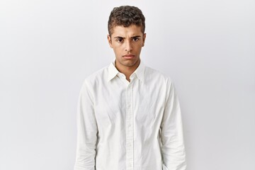 Wall Mural - Young handsome hispanic man standing over isolated background skeptic and nervous, frowning upset because of problem. negative person.