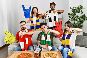 Sticker - Group of young people wearing team scarf cheering football game with angry face, negative sign showing dislike with thumbs down, rejection concept