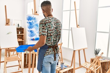 Wall Mural - Young african american artist man on back view painting with paint roller at art studio.