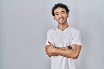 Wall Mural - Hispanic man standing over isolated background happy face smiling with crossed arms looking at the camera. positive person.