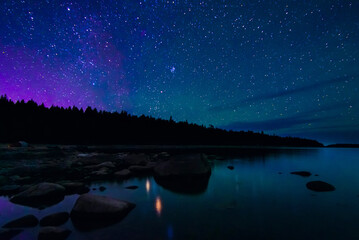 Wall Mural - night landscape with a starry sky and milky way over the water of a lake with stones