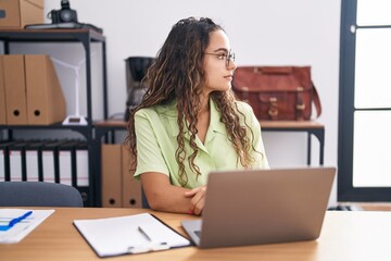 Sticker - Young hispanic woman working at the office wearing glasses looking to side, relax profile pose with natural face with confident smile.