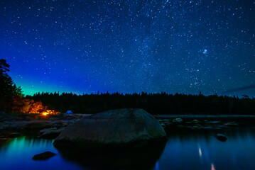 Wall Mural - night landscape with a starry sky and the milky way with stars and constellations over the water of 