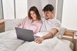 © Krakenimages.com - Mand and woman couple using laptop sitting on bed at bedroom